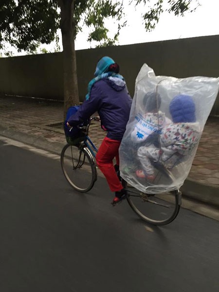 Giữa một sớm mai rét mướt, bức ảnh bé con ngồi sau xe bố trùm kín nilon khiếm lòng ta ấm áp